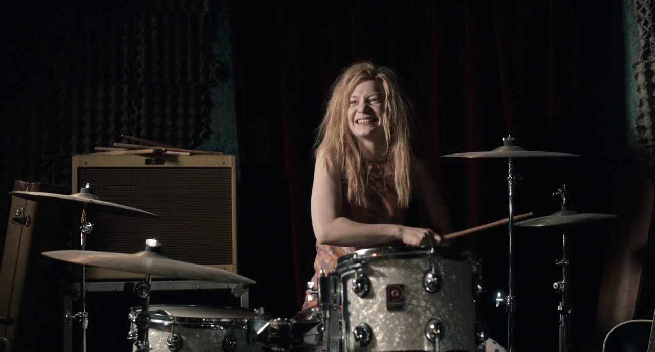 Only Lovers Left Alive (2013) movie still: medium — A dimly lit rehearsal space features dark red curtains and acoustic foam wall panels. A young…