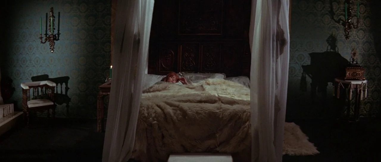 The Masque of the Red Death (1964) movie still: wide — A lavish room features patterned teal wallpaper and dark antique furniture under soft…