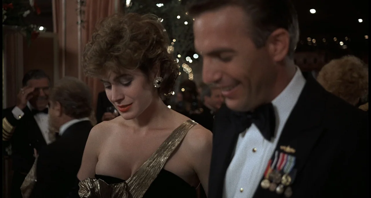No Way Out (1987) movie still: medium — A crowded ballroom with blurred string lights visible in the background reflection. A man in a tuxedo and a…