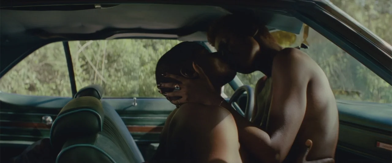 Queen & Slim (2019) movie still: medium — A vintage car interior bathed in natural sunlight shows two individuals close together. The two subjects…