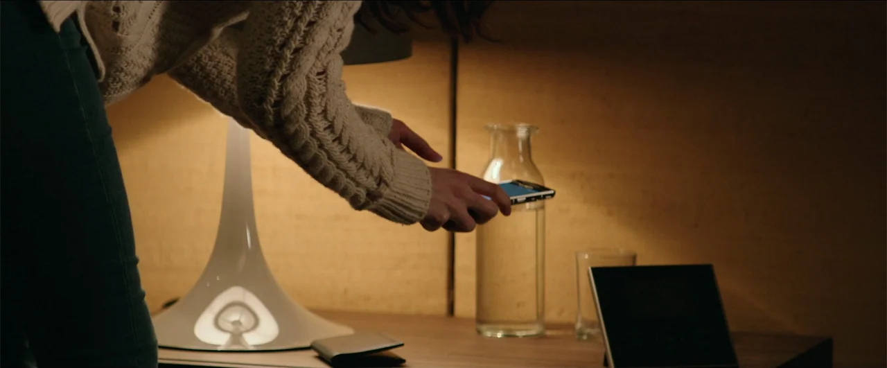 Fifty Shades Freed (2018) movie still: medium — A nightstand holds a glass water carafe and a small electronic clock in dim lighting. A woman…