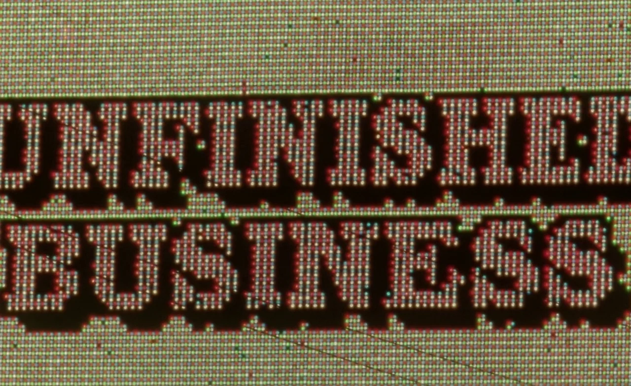 Leaving Las Vegas (1995) movie still: closeup — A close-up view of an electronic screen displaying the words UNFINISHED BUSINESS. The text is…