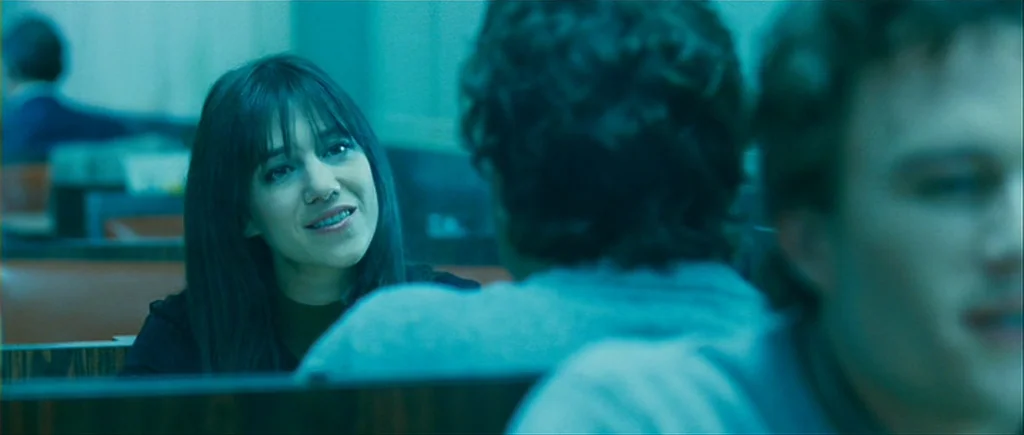 I’m Not There (2007) movie still: medium — A dimly lit diner booth features wood-paneled walls and low-contrast seating. A dark-haired woman speaks…