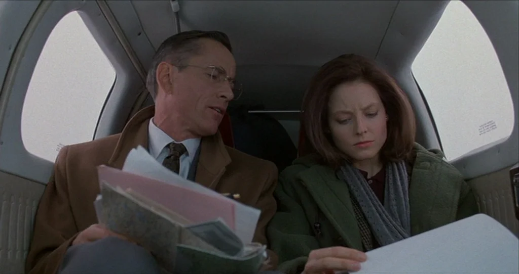 The Silence Of The Lambs (1991) movie still: medium — The interior of a small private plane with beige fabric walls and windows. A man and a woman…