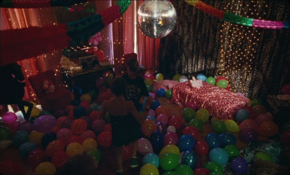 Misunderstood (2014) movie still: wide — A decorated bedroom is filled with numerous multi-colored balloons and hanging paper streamers. Two…