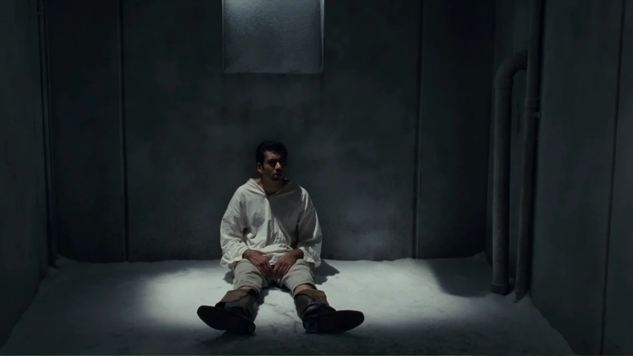 Epic Movie (2007) movie still: fullbody — A spartan stone chamber features gray walls, a high window, and exposed vertical piping. A man in period…