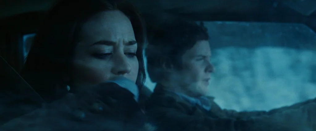 Wind Chill (2007) movie still: medium — The interior of a moving vehicle at night with blue tones throughout the cabin. A man drives while a woman…