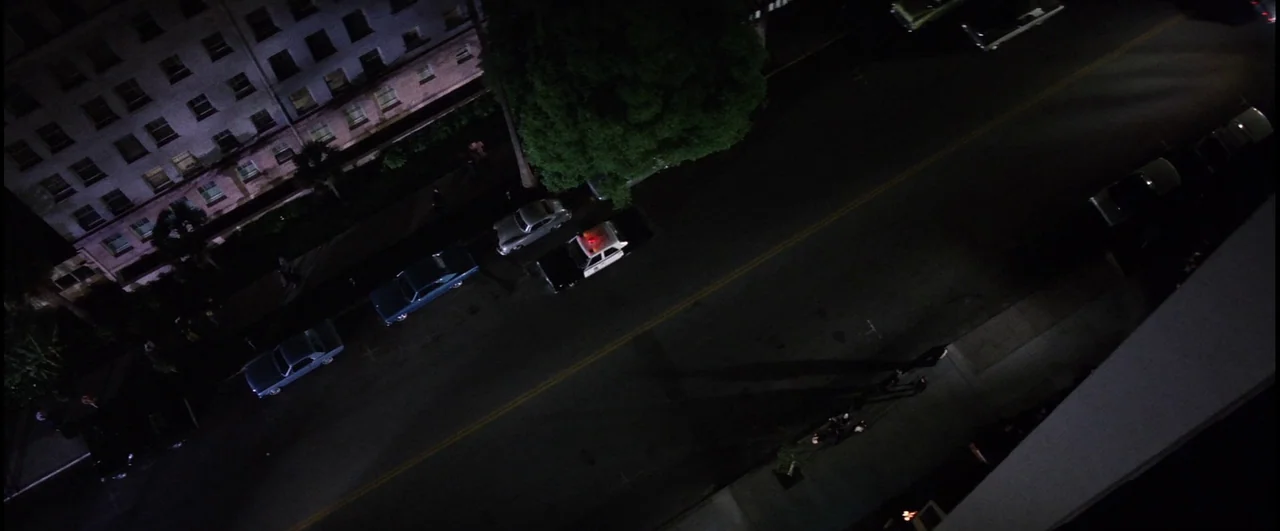 Point Blank (1967) movie still: establishing — An aerial night view of a quiet urban street lined with parked cars. A police cruiser with activated…