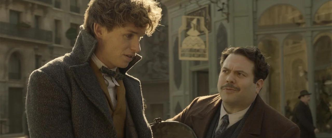 Fantastic Beasts: The Crimes of Grindelwald (2018) movie still: medium — A 1920s city street with ornate stone architecture and storefronts in the…
