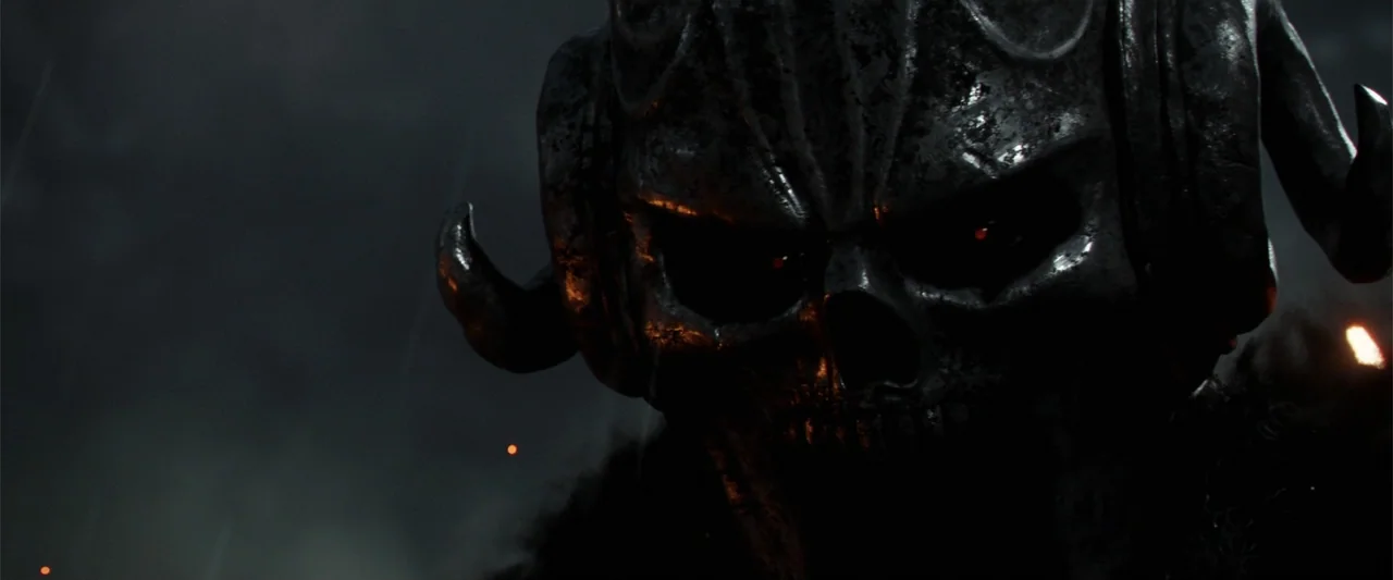 King Arthur: Legend of the Sword (2017) movie still: closeup — A dark, smoke-filled battlefield is illuminated by distant fires in the night air. A…