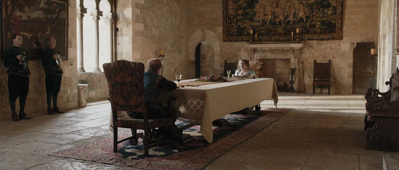 Tale of Tales (2015) movie still: wide — A spacious stone hall features vaulted ceilings and light filtering through tall arched windows. A man and…