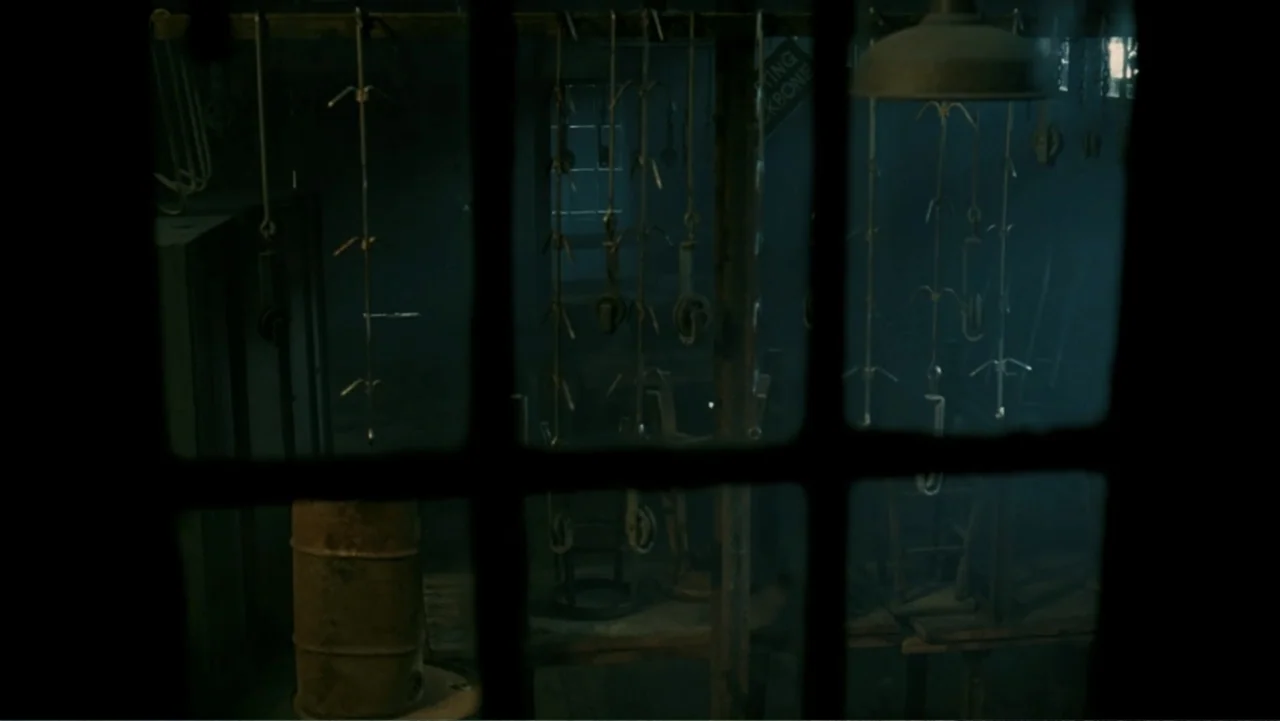 The Texas Chainsaw Massacre: The Beginning (2006) movie still: establishing — A dark, industrial interior contains rows of metal hooks hanging from…