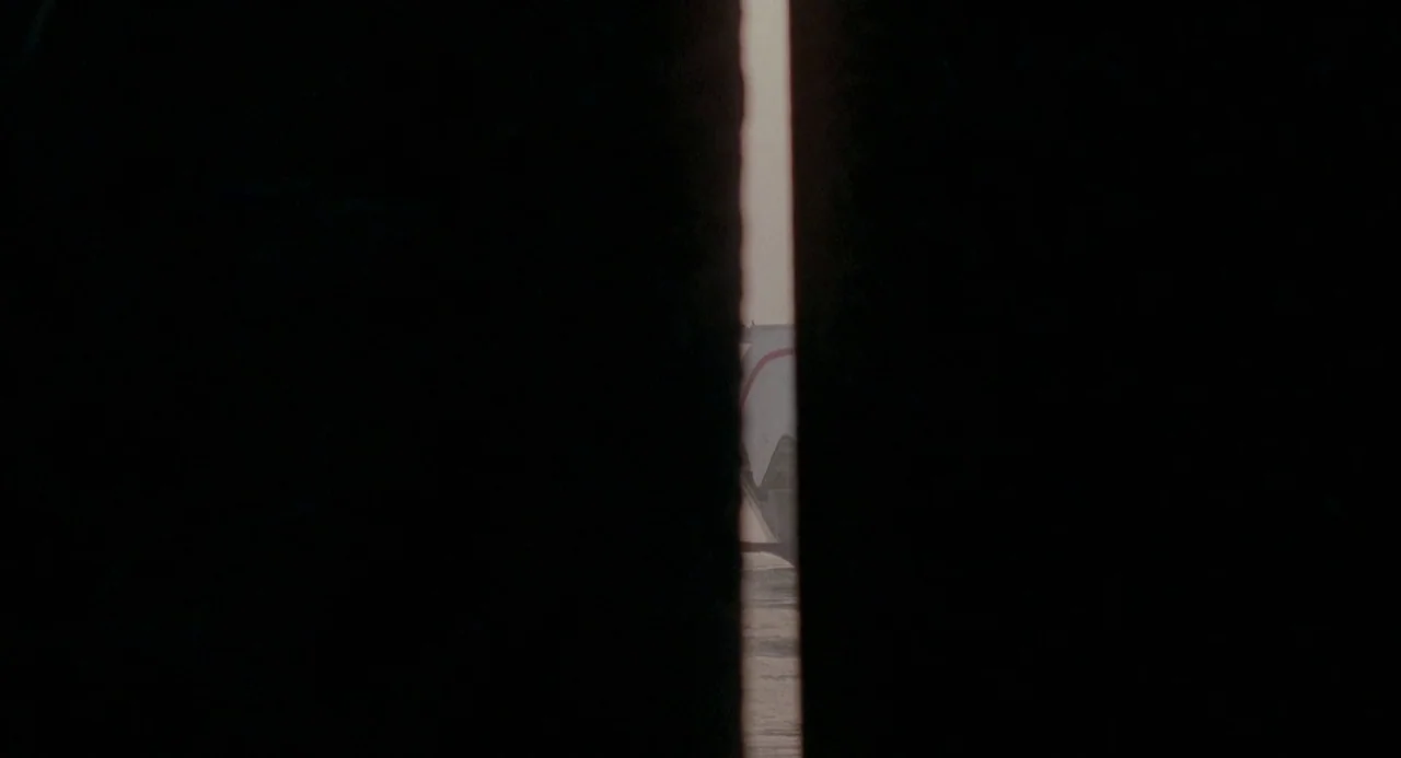 Three Colours: Red (1994) movie still: wide — A vertical sliver of daylight appears between two heavy, dark foreground objects. A small patch of…