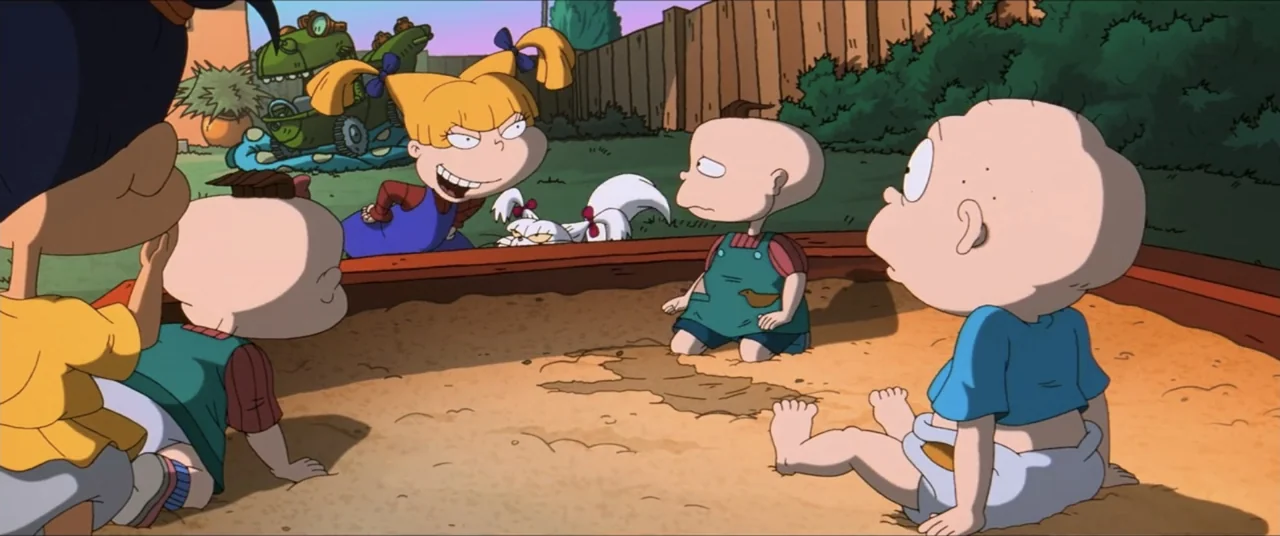 Rugrats Go Wild (2003) movie still: medium — A sunny backyard contains a wooden-framed sandbox filled with sand and four toddlers.