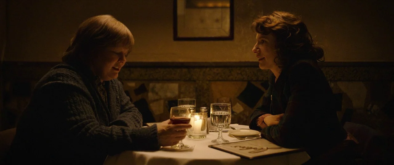 Can You Ever Forgive Me? (2018) movie still: medium — A dimly lit restaurant booth with a white tablecloth and warm candle centerpieces. Two women…