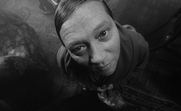 The Cremator (1969) movie still: closeup — An interior space viewed from a steep high-angle perspective looking down at a man. The subject stares…