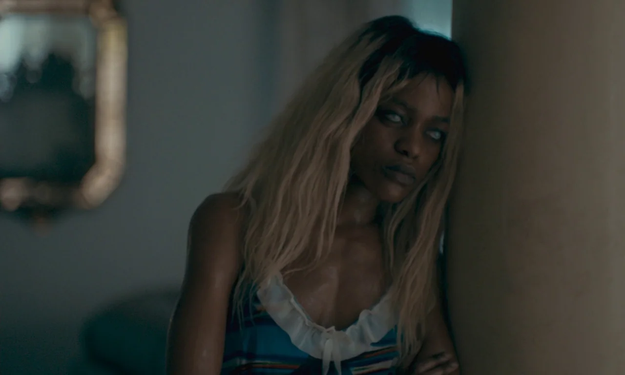 Atlantics (2019) movie still: medium — A dimly lit indoor space with blurred architectural elements in the background. A woman with long blonde hair…