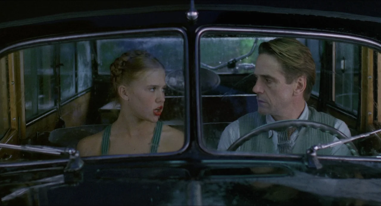 Lolita (1997) movie still: medium — The interior of an vintage car during a rainy day. A young woman and an older man are seated inside the vehicle…