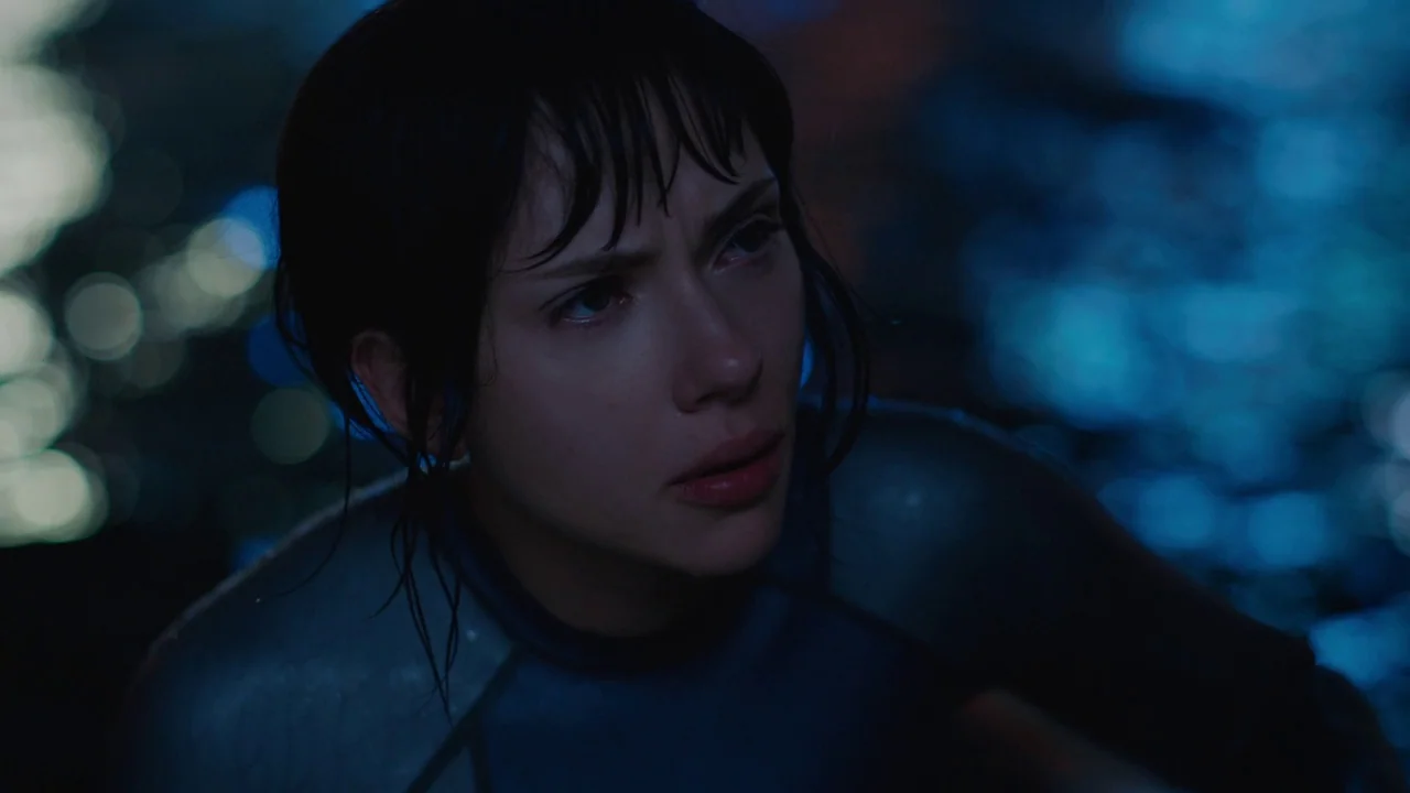 Ghost in the Shell (2017) movie still: closeup — A woman with wet hair faces slightly away from the camera in dark water. Reflections of distant…