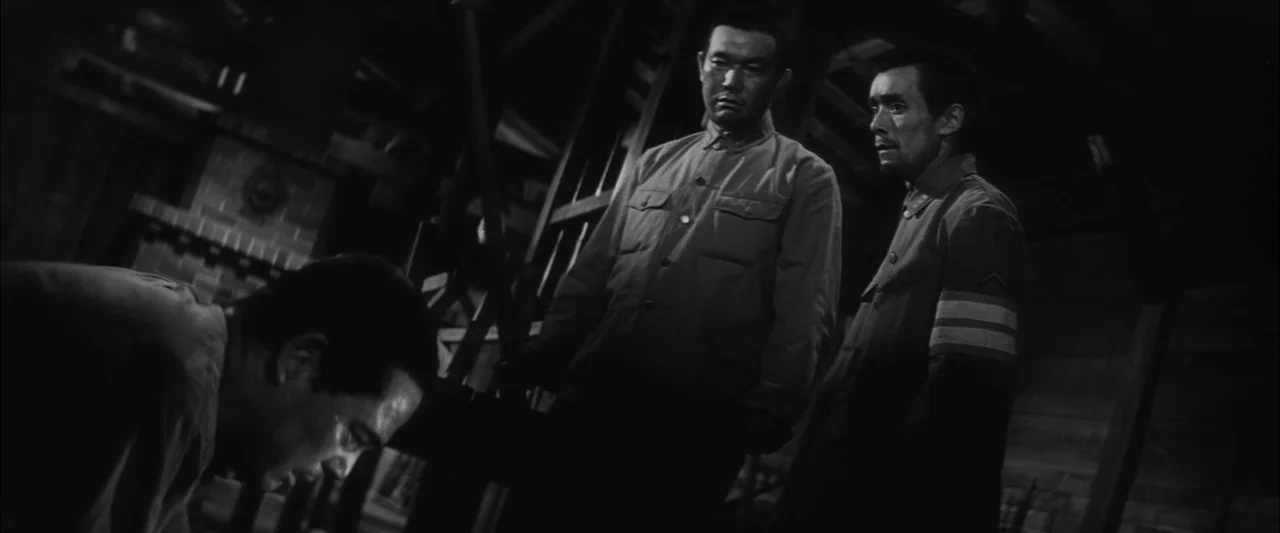 The Human Condition II: Road to Eternity (1959) movie still: medium — A dark wooden room contains three men in a tense military-style interaction.…