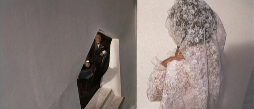 Boom! (1968) movie still: medium — A woman in a white lace veil stands on a staircase looking down. A man in a suit stands on a lower landing,…
