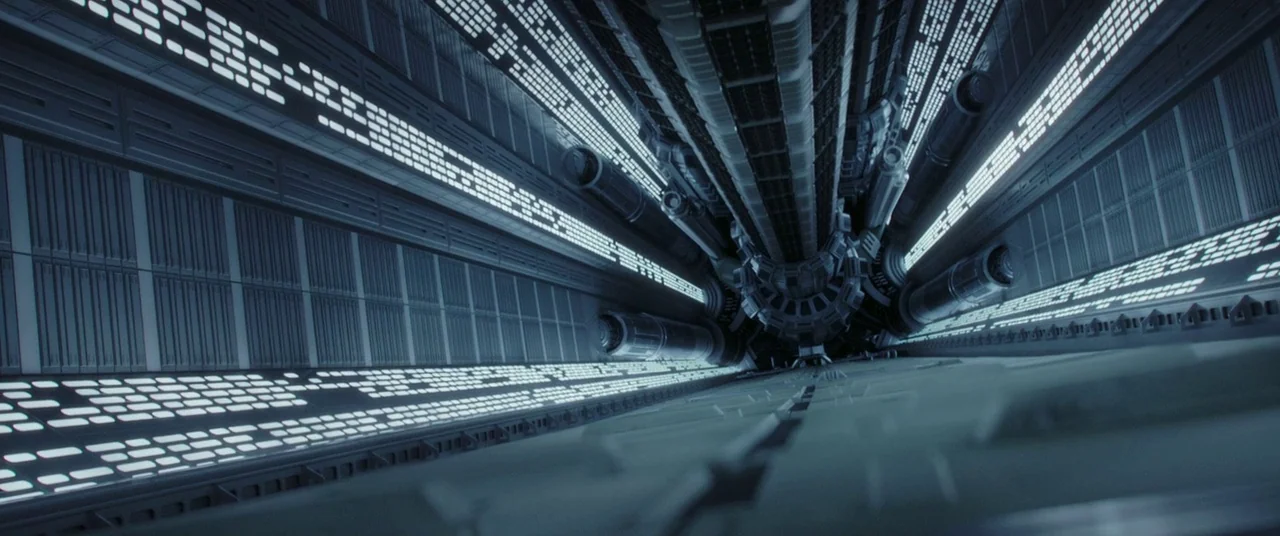 Rogue One: A Star Wars Story (2016) movie still: establishing — A long, metallic corridor inside a futuristic spaceship stretches into the distance.…