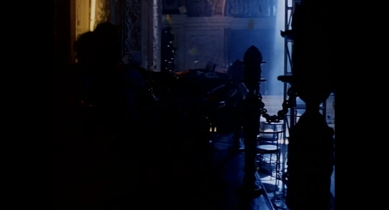 American Yakuza (1993) movie still: wide — A dark, ornate interior space features tall decorative pillars and a blue light shaft. Empty room with no…