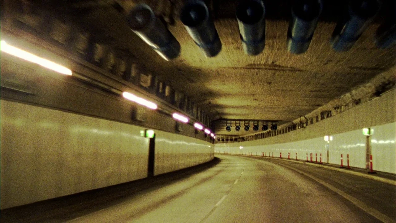 Pusher III (2004) movie still: establishing — A curved road tunnel features white tiled walls and concrete ceilings with ventilation ducts. The…