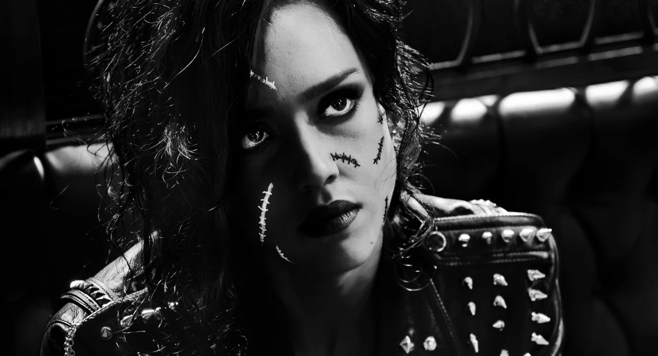 Sin City: A Dame to Kill For (2014) movie still: closeup — A dark booth in a dim space features black leather tufted upholstery. A woman with…