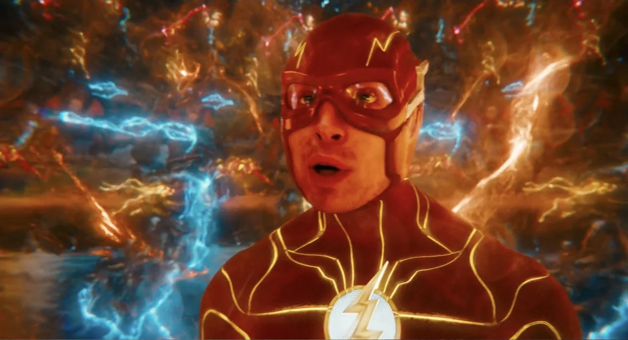 The Flash (2023) movie still: closeup — A figure in a red superhero suit stands within a glowing, turbulent energy field. The subject has an…