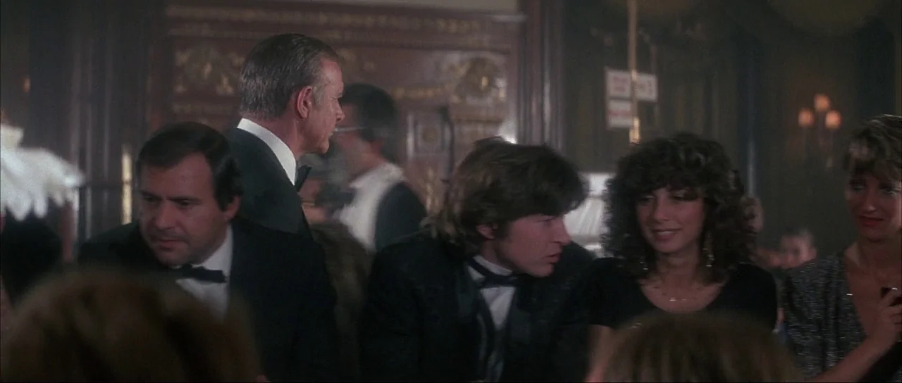 Never Say Never Again (1983) movie still: medium — A crowded, dimly lit hall features ornate wooden wall panels with intricate decorative gold…