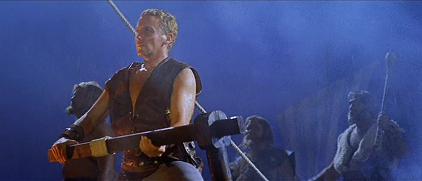 Erik The Conqueror (1961) movie still: medium — A wooden tiller on the deck of a ship at night under blue light. Several men with beards operate the…
