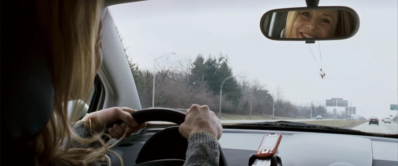 No Reservations (2007) movie still: medium — The interior of a car driving along a highway during an overcast day. A woman in a grey sweater holds…
