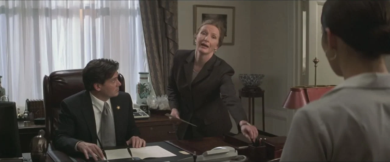 Maid in Manhattan (2002) movie still: medium — An office features a wooden desk, window with white curtains, and framed wall art. A woman stands by…