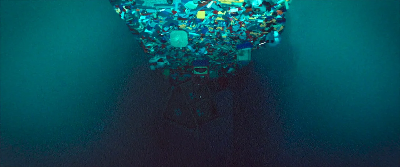 Skinamarink (2022) movie still: wide — A dense cluster of colorful plastic building bricks slowly sinks through murky deep water. The debris casts…