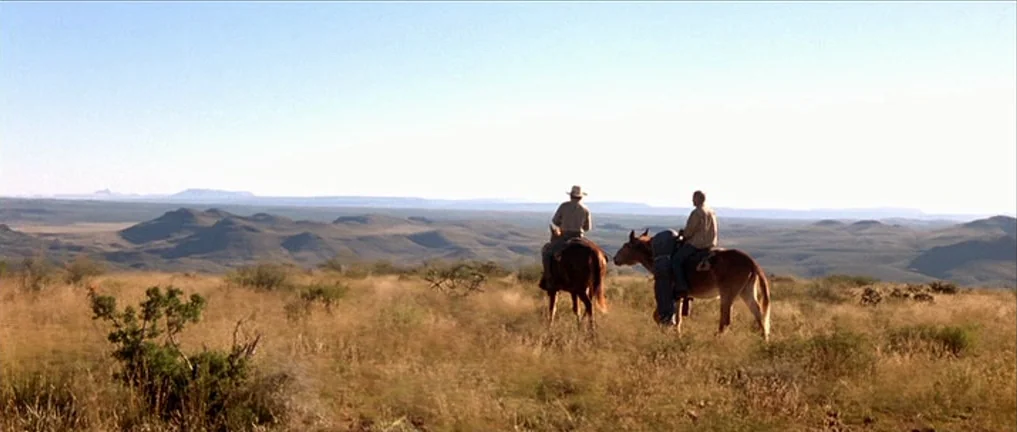 The Three Burials of Melquiades Estrada (2005) movie still: wide — An arid, rolling desert plain stretches toward a distant, low-lying horizon line.…
