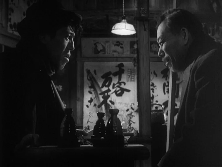 Ikiru (1952) movie still: medium — A dark wooden establishment features a wall poster with Japanese calligraphy and ceramic bottles. Two men sit at…