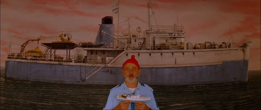 The Life Aquatic With Steve Zissou (2004) movie still: medium — A man stands before a two-dimensional painted backdrop depicting a boat on water.…