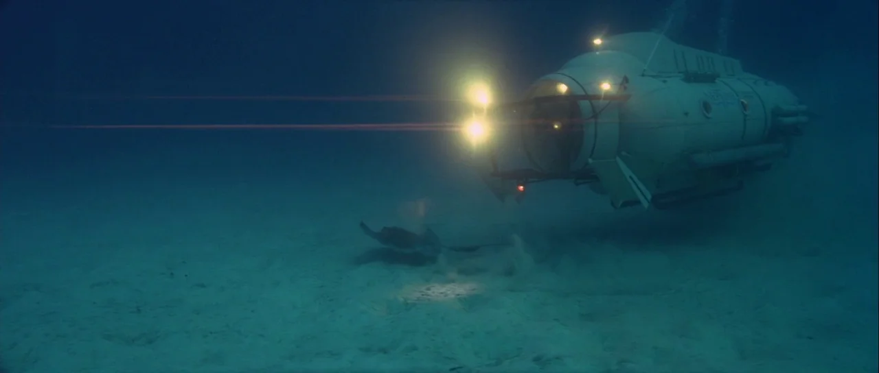 For Your Eyes Only (1981) movie still: wide — A dark, expansive underwater landscape features a sandy sea floor in dim, murky water. A white…