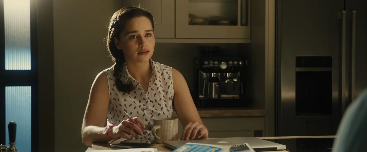 Me Before You (2016) movie still: medium — A modern kitchen interior features light gray cabinets, a stainless steel refrigerator, and an espresso…