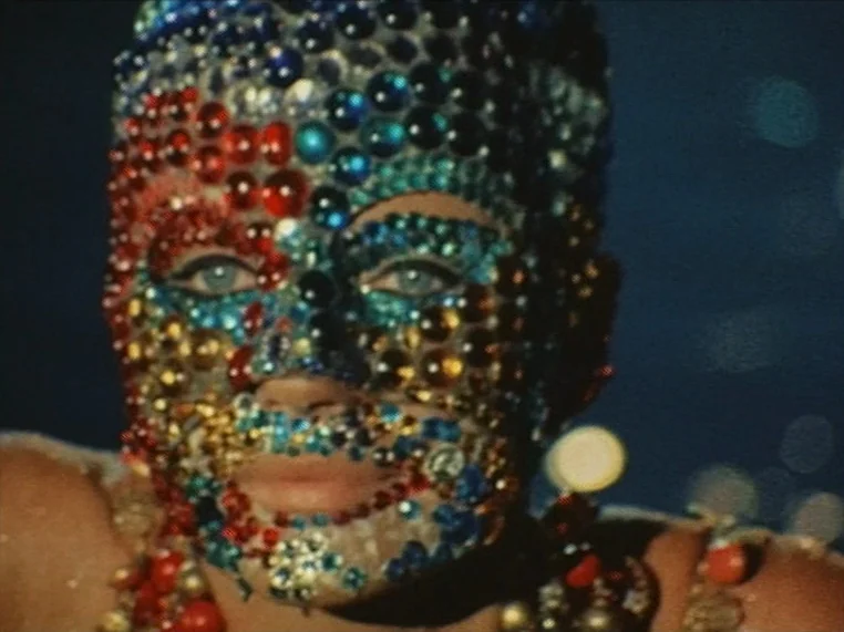 Salome (1972) movie still: closeup — A close-up view of a woman against a dark, out-of-focus background. Her entire face and shoulders are covered…