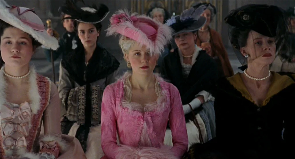 Marie Antoinette (2006) movie still: medium — A group of women in 18th-century attire sit in a large, stone-walled chamber. They watch proceedings…