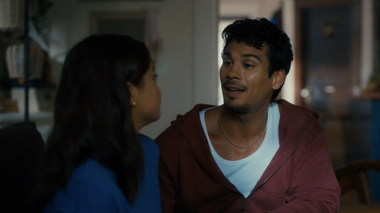 Sidelined: The QB and Me (2025) movie still: medium — A residential living room interior with soft ambient light fills the space. A man in a maroon…