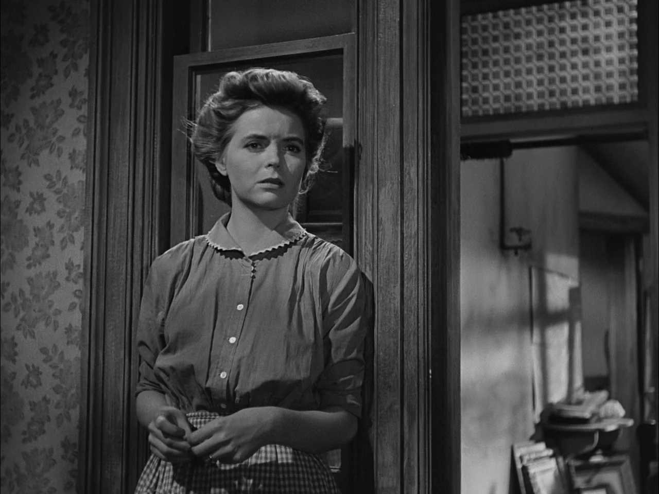 A Tree Grows In Brooklyn (1945) movie still: medium — A domestic interior features a woman standing in a dark wood door frame. The surrounding walls…