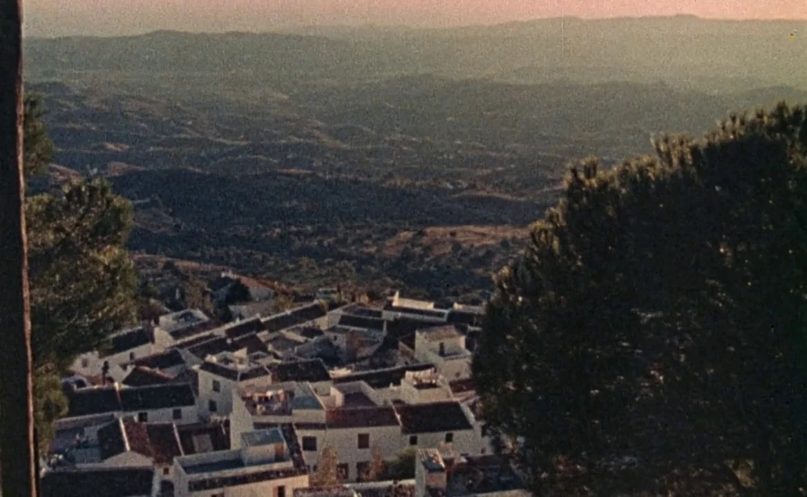 F for Fake (1973) movie still: establishing — A cluster of white-washed houses with terracotta roofs sits nestled on a hilly slope. Rolling…