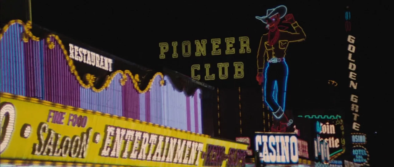 Diamonds Are Forever (1971) movie still: wide — Multiple illuminated neon signs line a street at night in Las Vegas. The signs advertise the Pioneer…