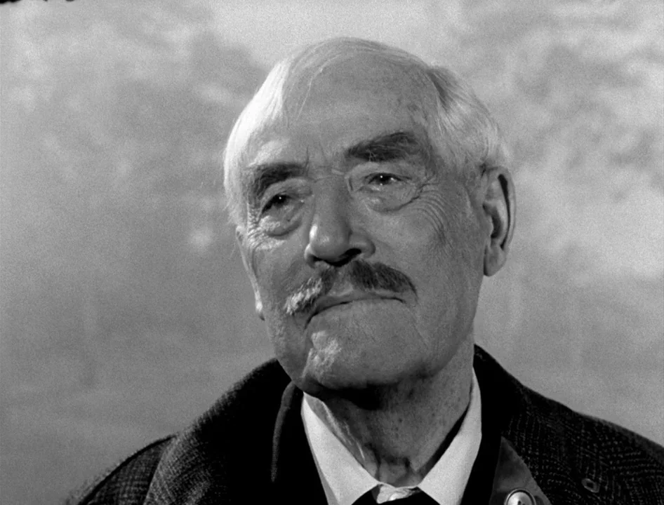 Wild Strawberries (1957) movie still: closeup — An elderly man is framed in a close-up against a plain, light-colored background. He looks slightly…