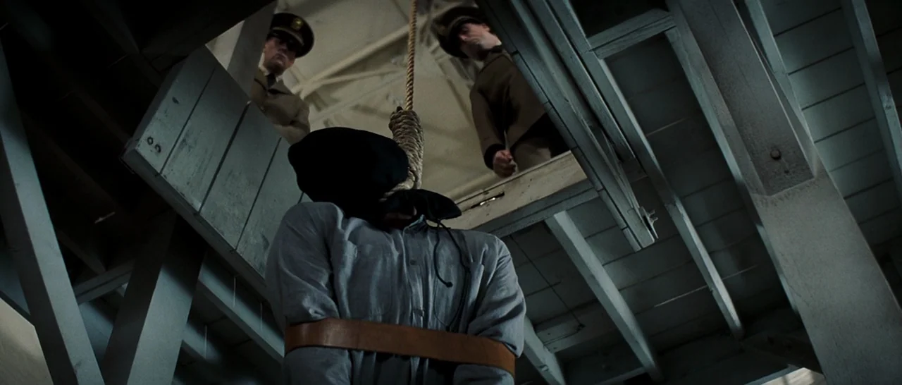 Changeling (2008) movie still: medium — A wooden gallows platform stands under a bright sky with two men observing from above. The condemned man…