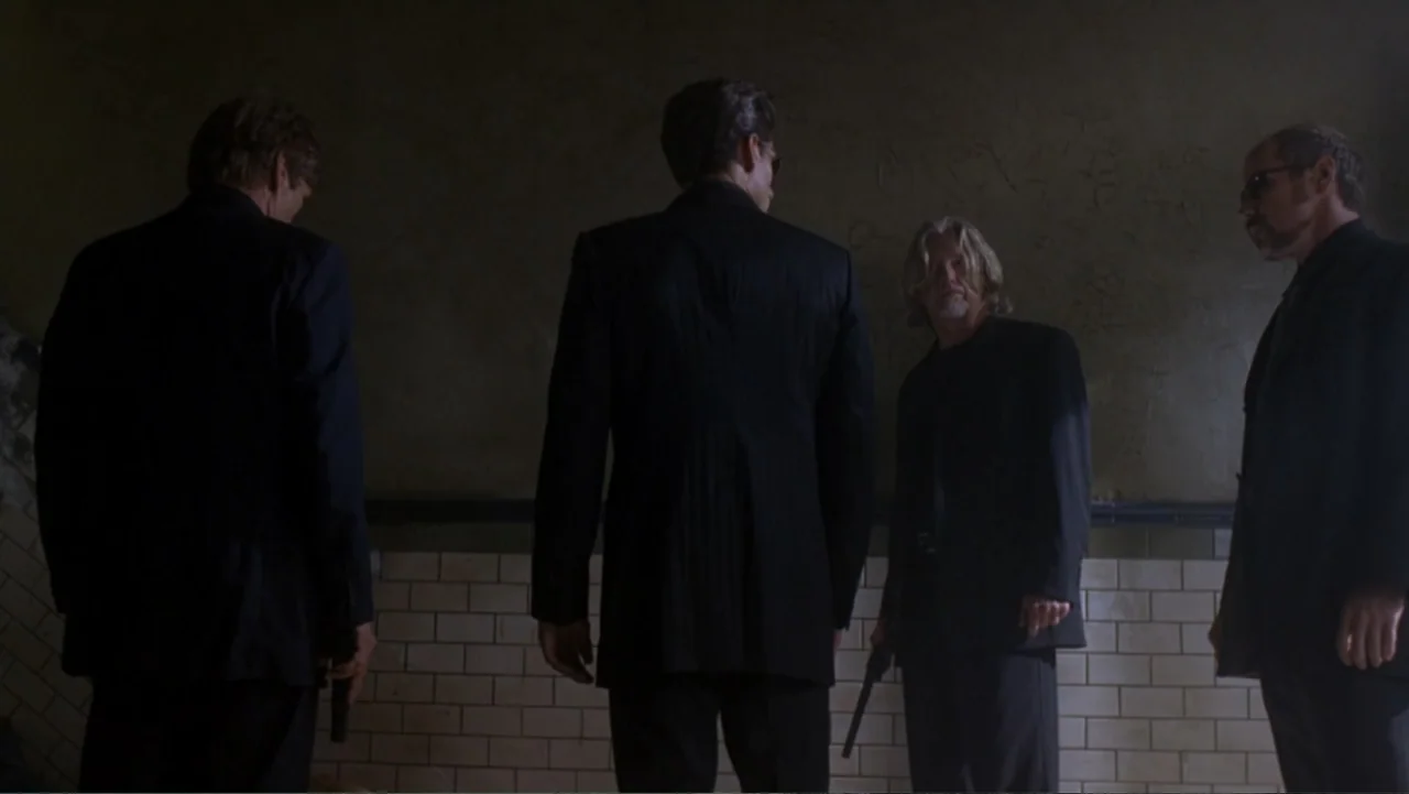 The Punisher (2004) movie still: fullbody — A dimly lit room features white tiled walls and a dark concrete floor. Four men in black suits holding…