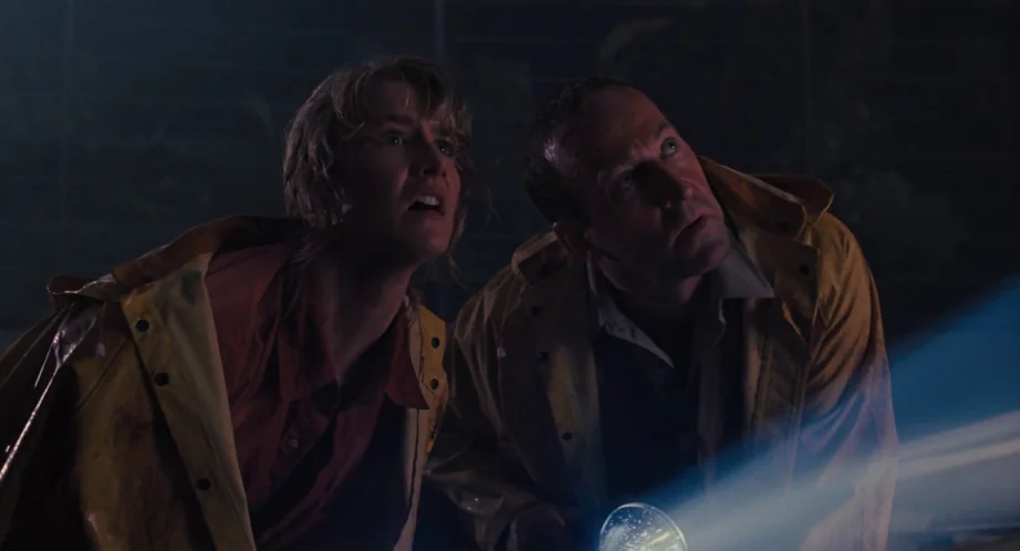 Jurassic Park (1993) movie still: medium — A dark, rainy outdoor location at night with low visibility. Two people in yellow rain slickers look…